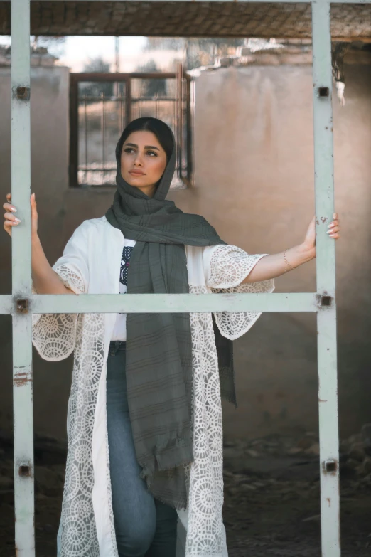 a woman in grey scarf and white top leaning on metal bars