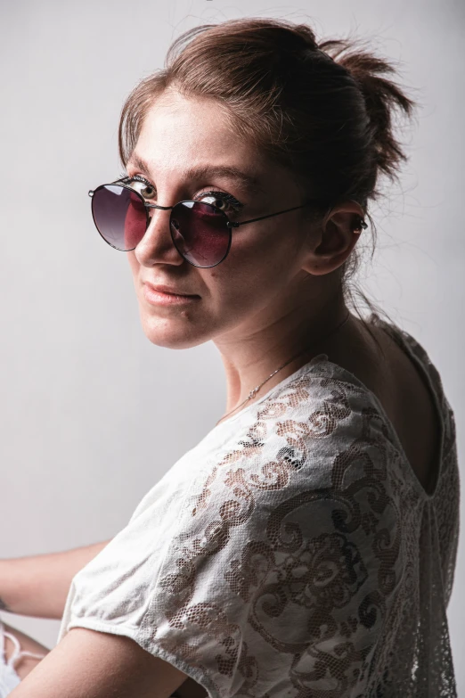 a woman posing in the sun wearing sunglasses