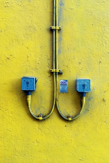 a yellow wall has two square blue plugs on it