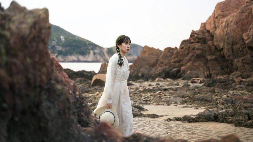 a woman with a white hat walking along a beach