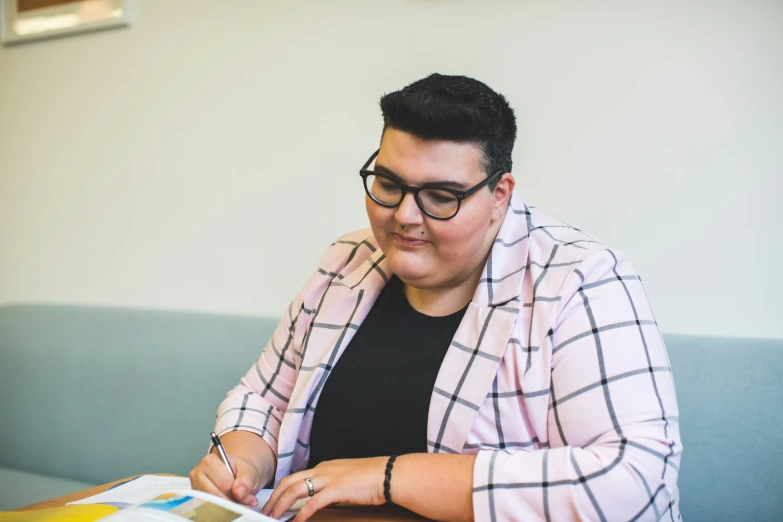 a woman sitting in front of a desk writing