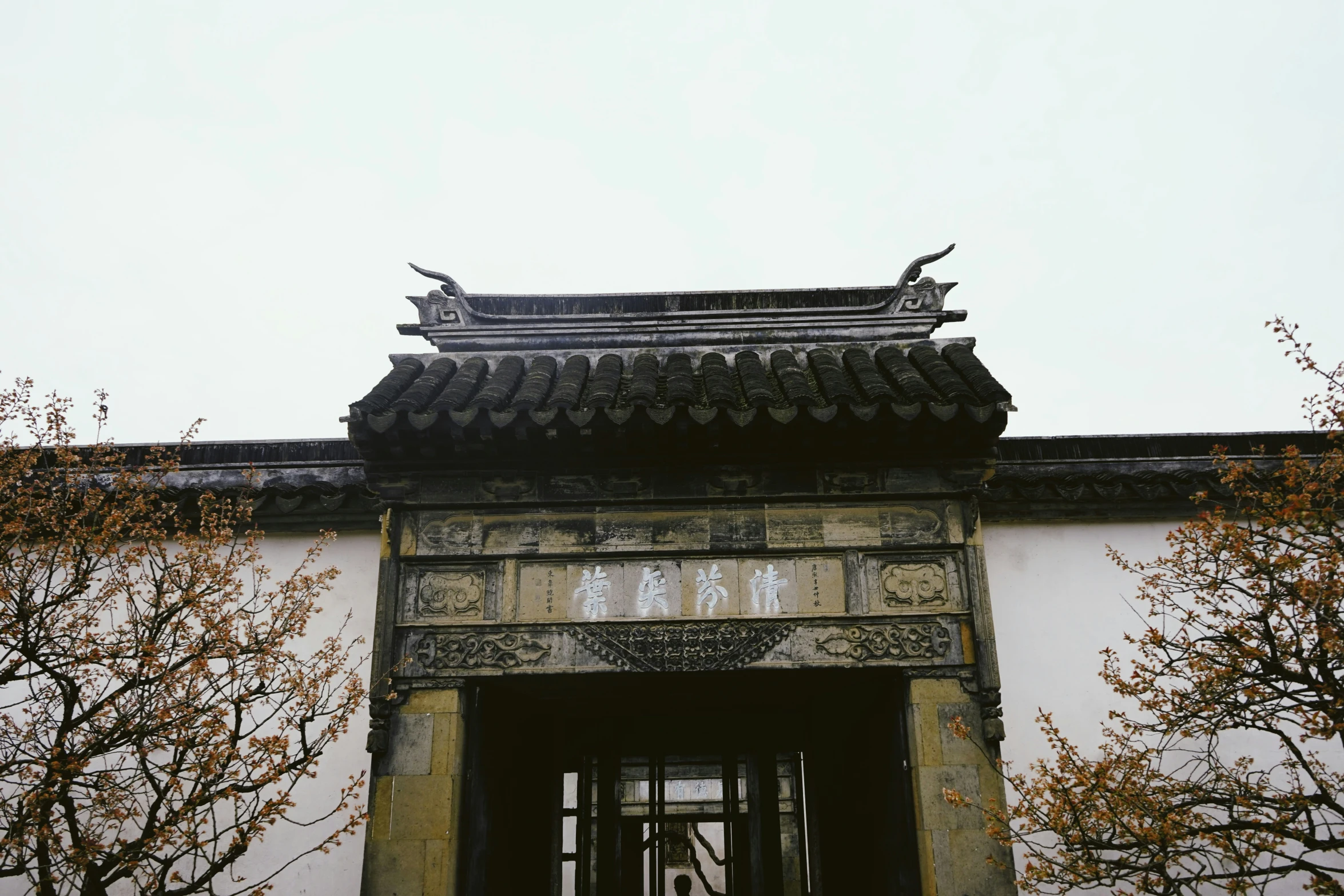 an oriental structure above trees and shrubs on a sunny day