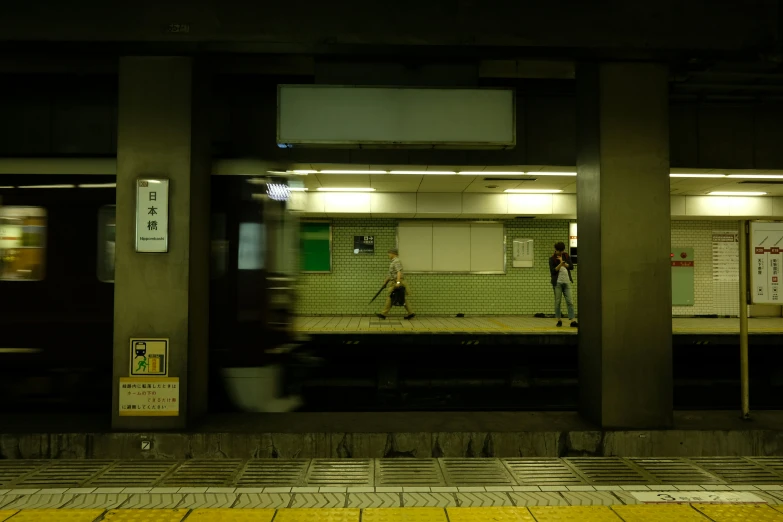 a train station in tokyo, japan, showing a man standing at the platform