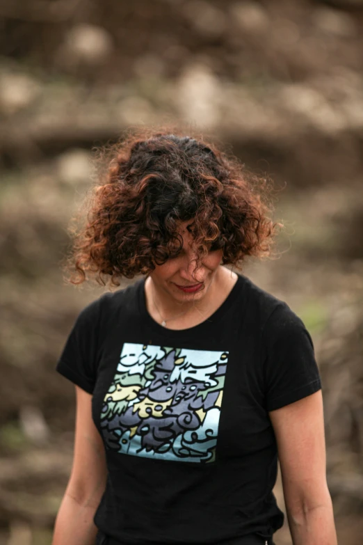 a young woman with curly hair is looking down