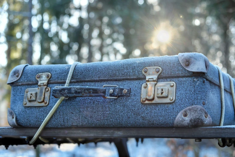 a denim piece of luggage sitting on top of a wooden bench