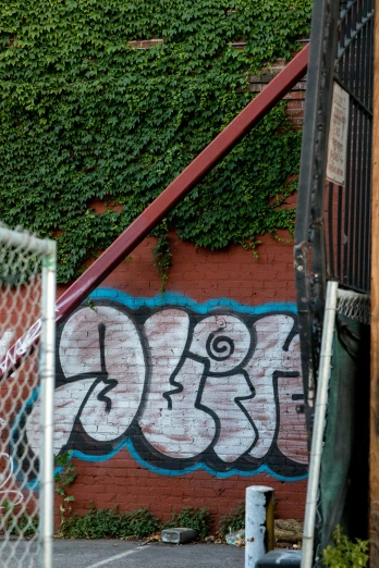 graffiti written on the side of a wall near a gate