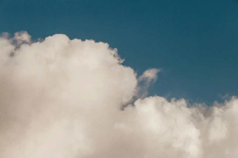 the plane is flying among a cloud filled sky