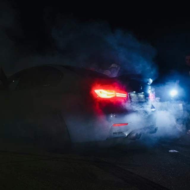 a man standing next to the back of a car at night