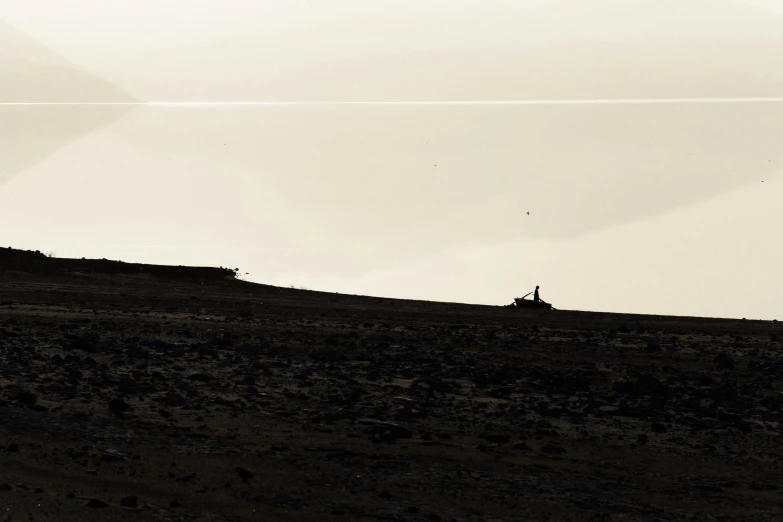 a silhouette of two people flying kites on a hill