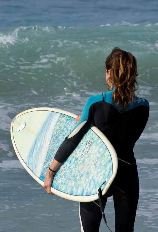 a woman carrying a surfboard standing on the beach