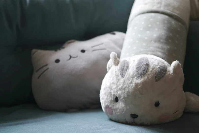 the cat doll is laying next to the white kitty pillow