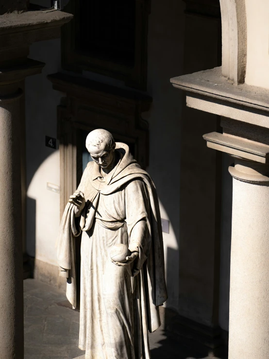 the statue is wearing a white cape next to pillars