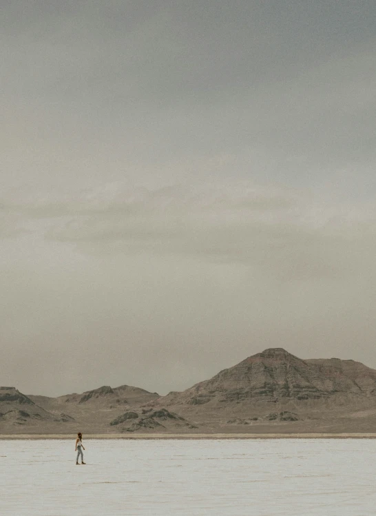 a person walking in an empty lot looking at a mountain range