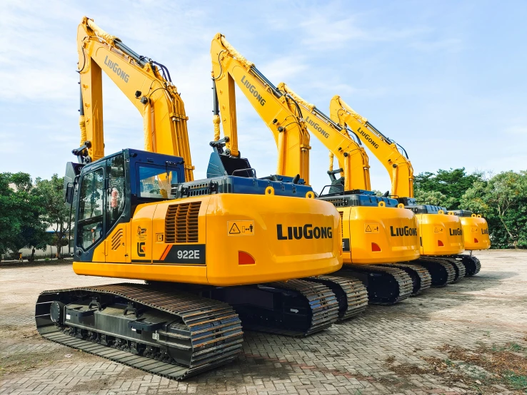 several yellow and black machines parked in front of trees