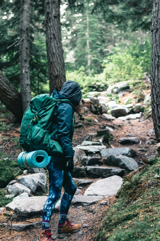 person wearing a backpack, with a blue bag on one shoulder and a water bottle in the other