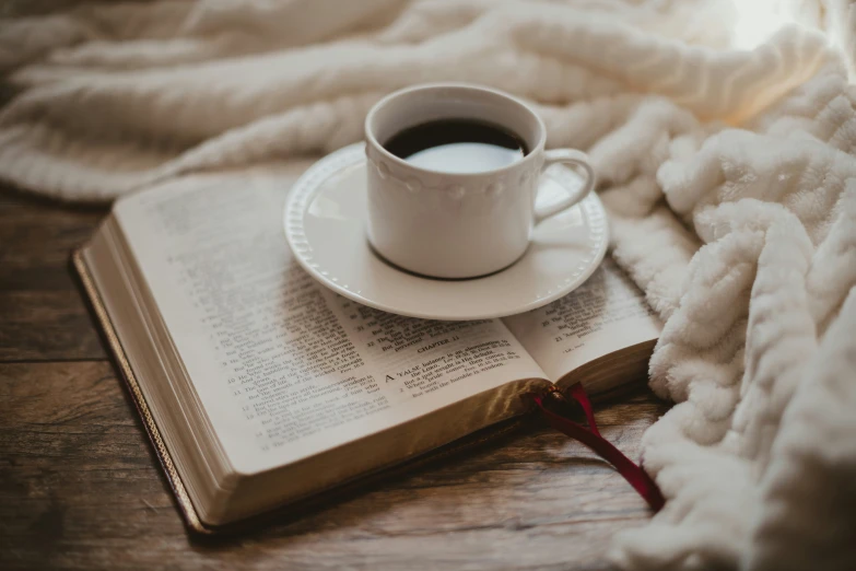 a cup of coffee sits on an open book