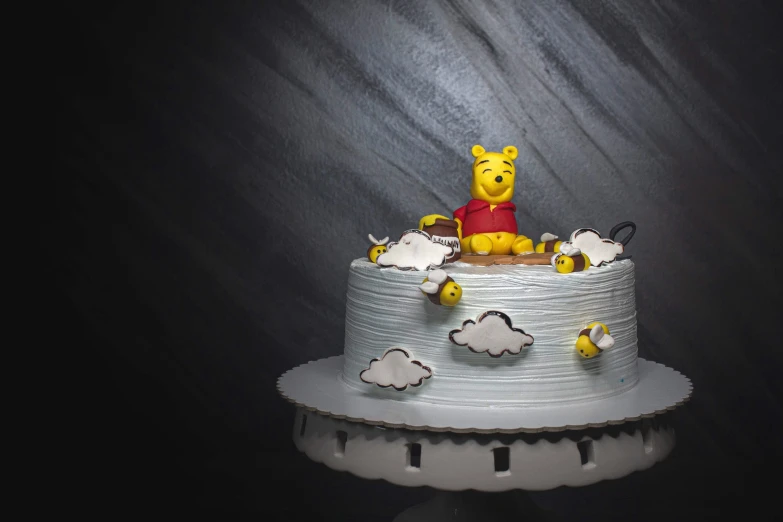 a cake sitting on top of a table with a winnie the pooh figure