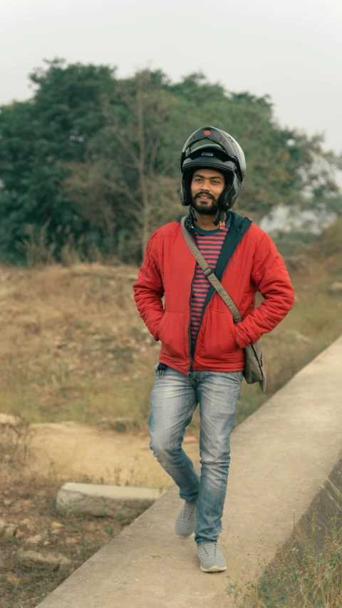 a man with a helmet and sweater is walking