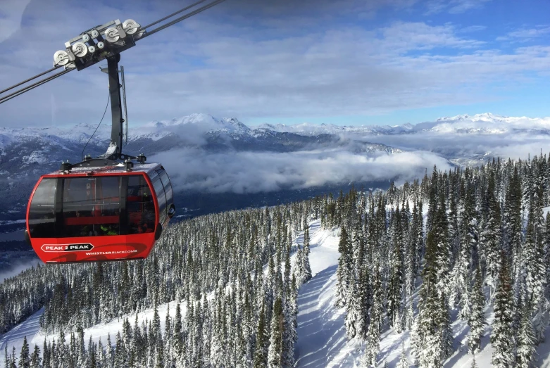 a red ski lift traveling over snow covered trees