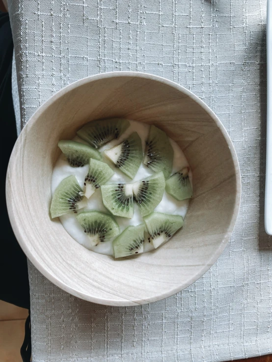 kiwis and other fresh fruit are in a wooden bowl