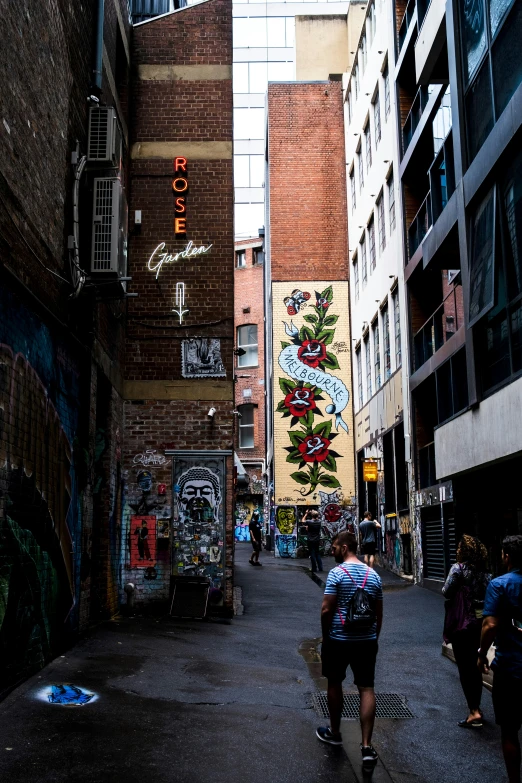 a couple walking in a street with graffiti on the side