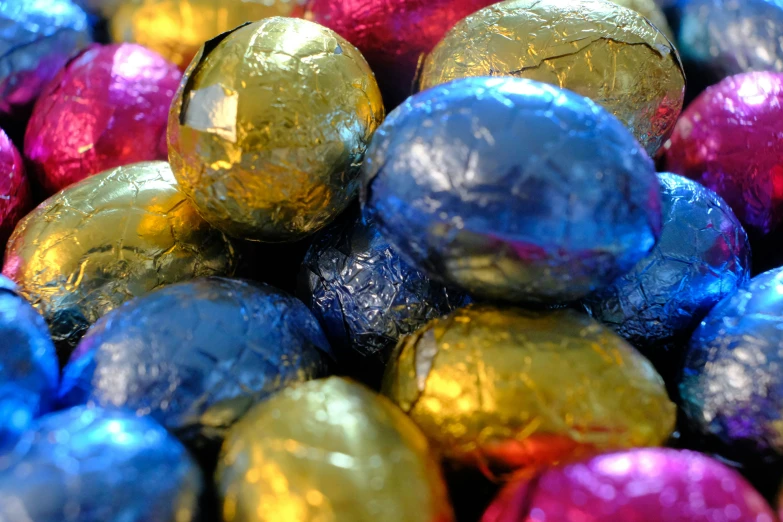 assorted metallic foiled chocolate eggs are in a bowl