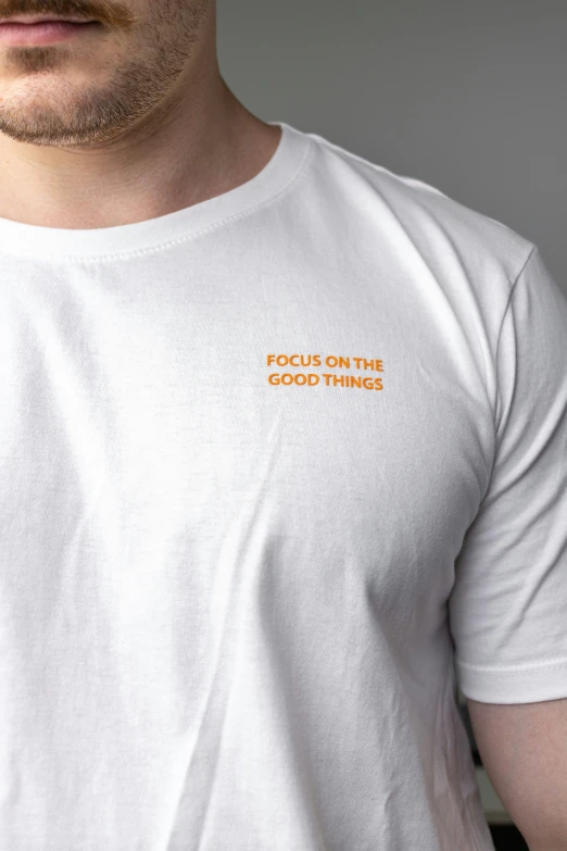 a man in a white t - shirt has an orange text across the chest