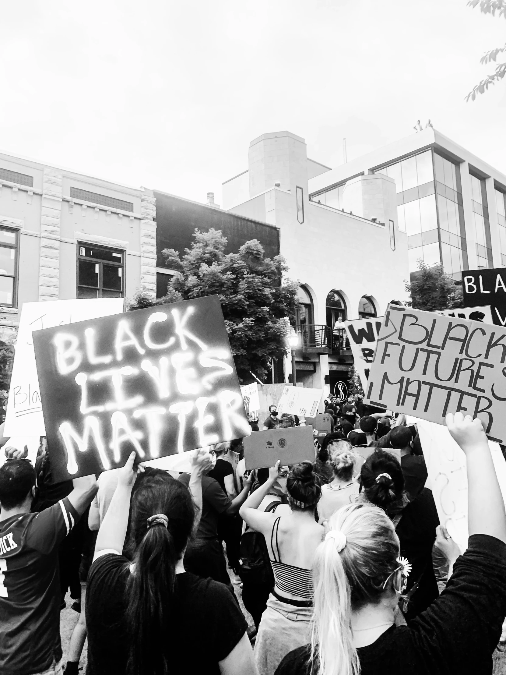 a group of people standing on a city street holding up a sign that says black lives matter