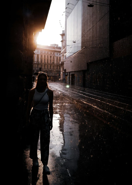 a woman in white shirt standing on sidewalk under umbrella