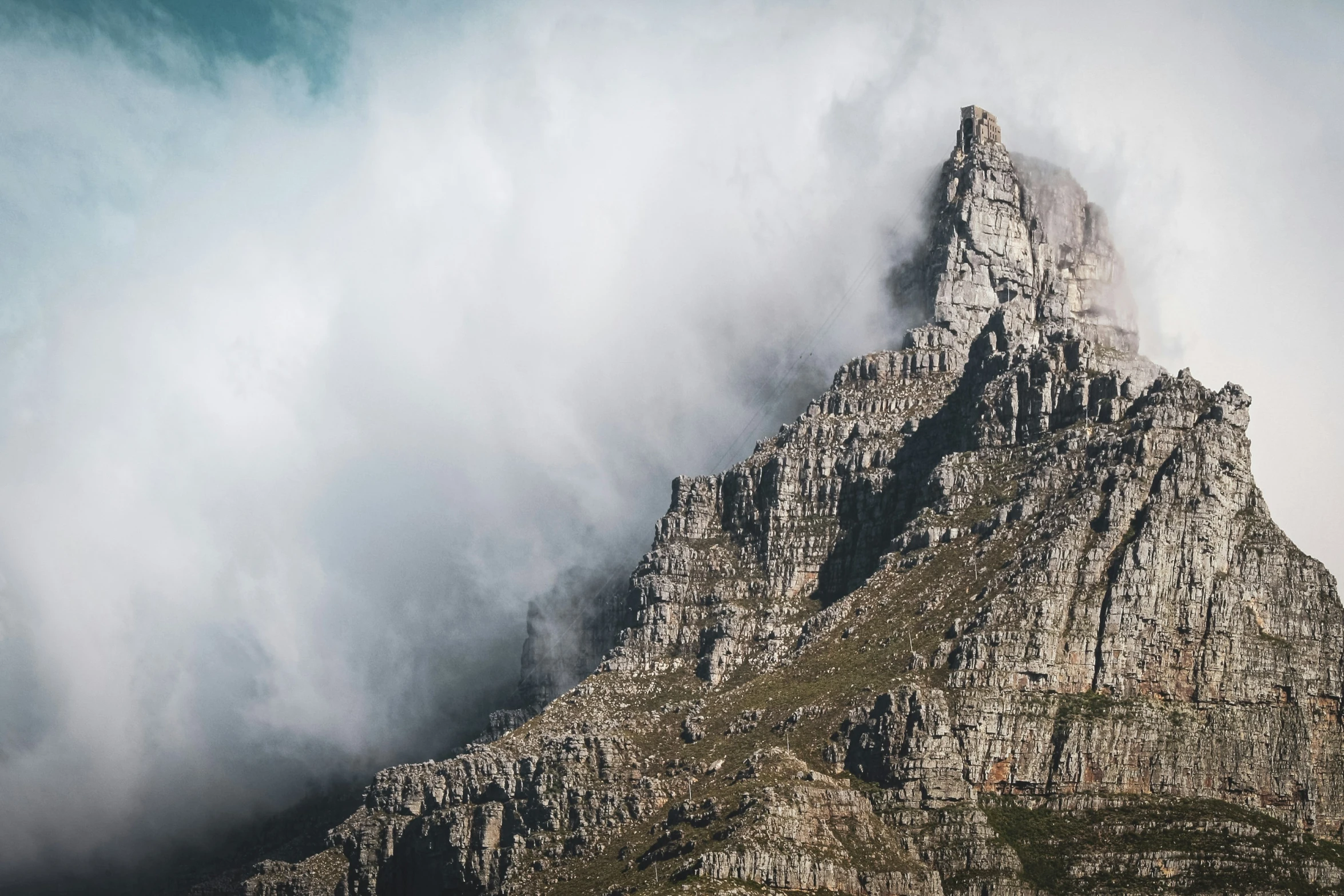 a mountain that is very tall with some clouds coming over it