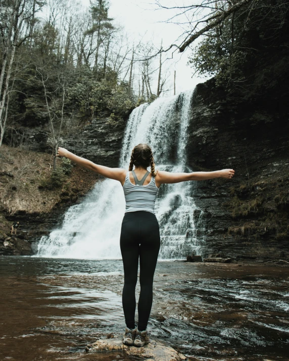 a person standing on the edge of a river with their arms out