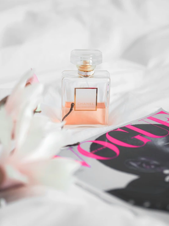 a book and perfume sitting on a bed