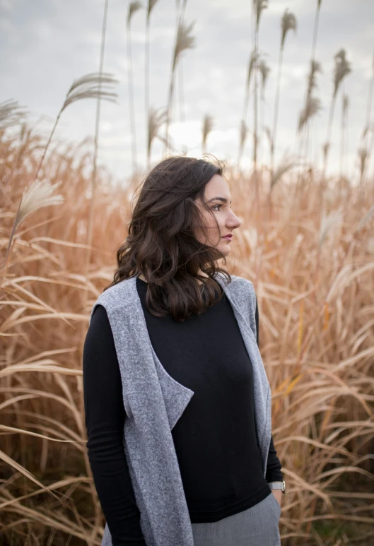 a woman standing in a field looking off into the distance