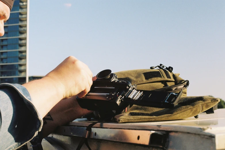 a man is holding an analog camera next to a backpack