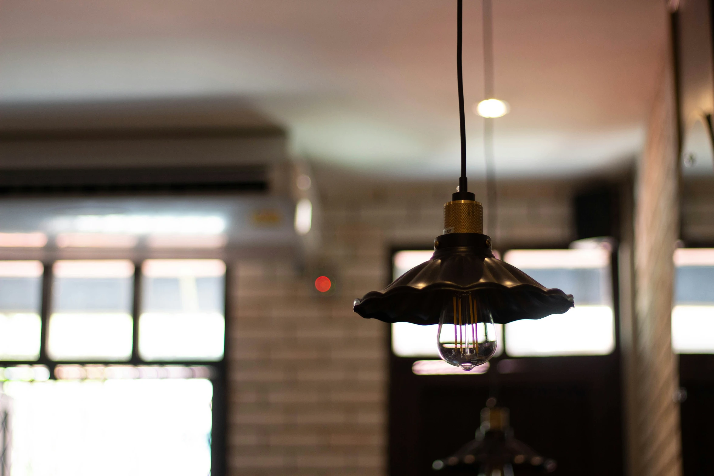 the light bulb hangs from the ceiling in front of some windows