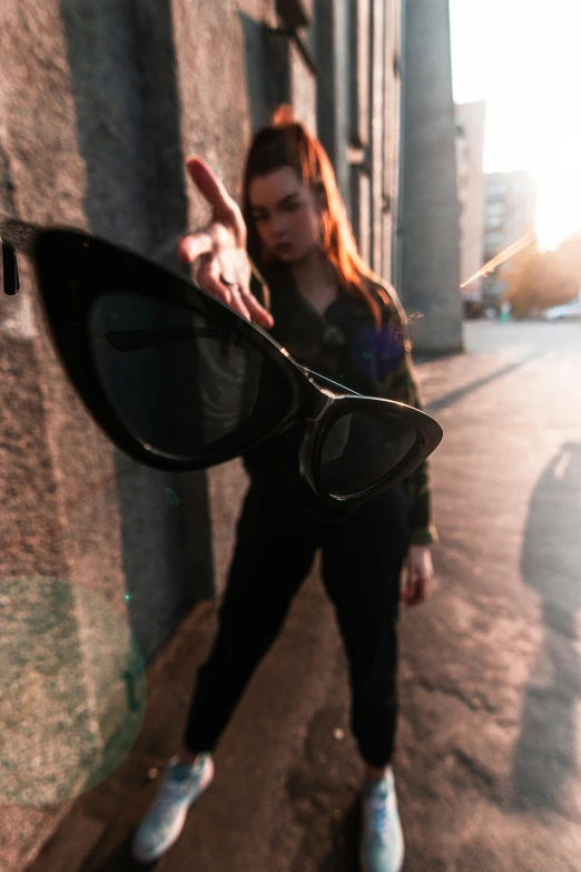 a young woman is leaning on a building with her reflection in a pair of sunglasses