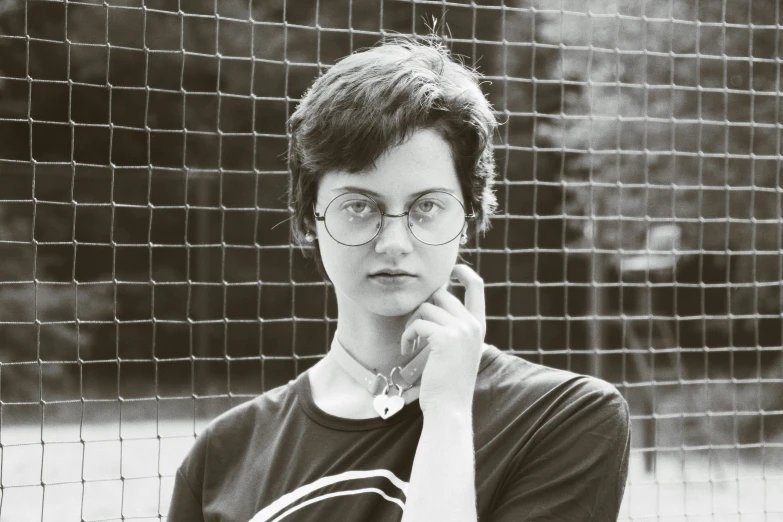 a girl with glasses and a chain link fence