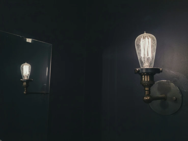 an antique style wall mounted light illuminates the dark side of a bathroom