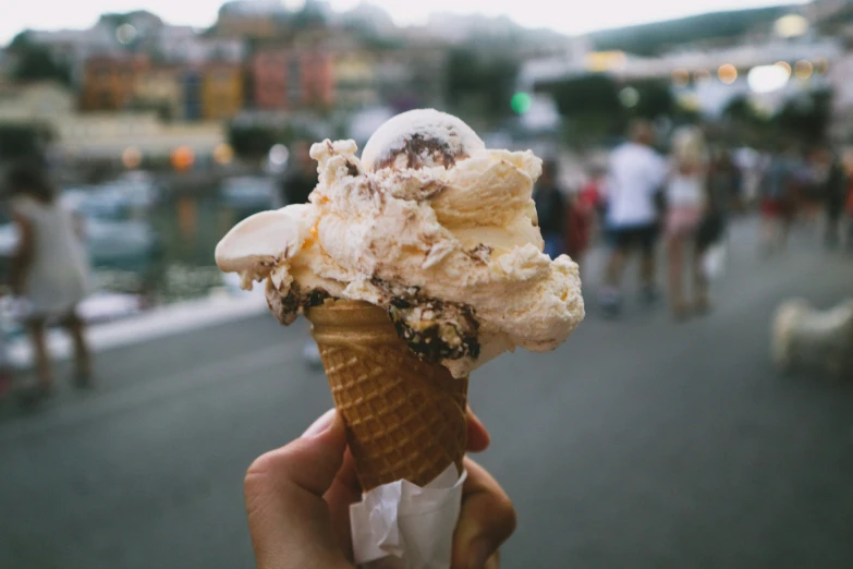someone holds an ice cream cone that is mostly white and chocolate