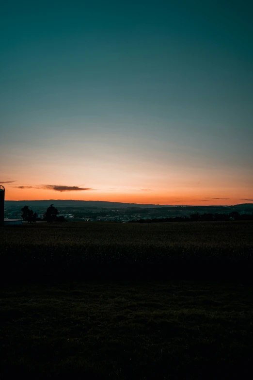 an orange and blue sunset over a field