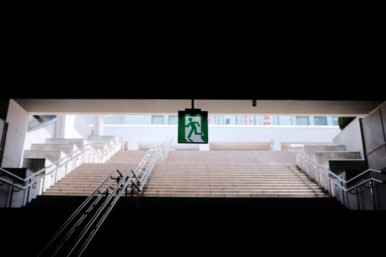 there is a green sign indicating that people are walking up the stairs