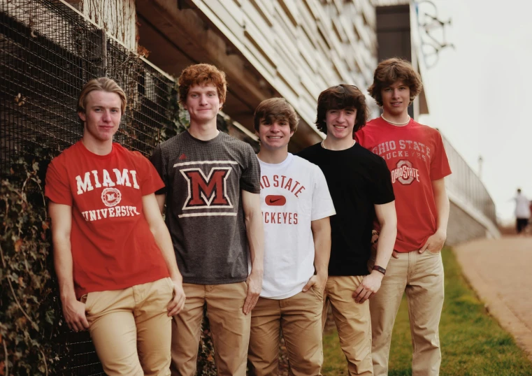 five teenage boys wearing red and black poses for a po