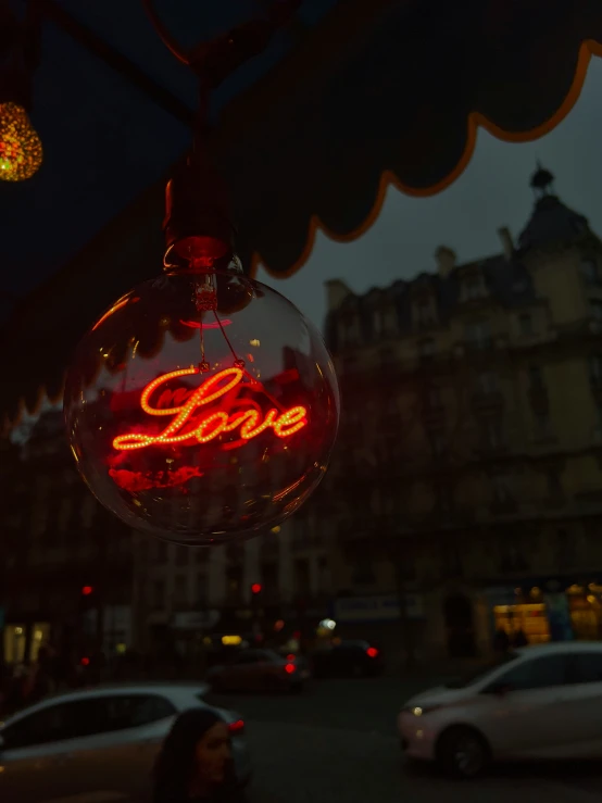 hanging glass ornament with a neon sign stating love