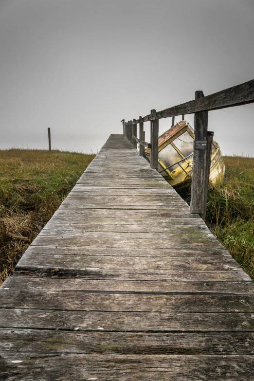 a wooden path leading to a boat in a field