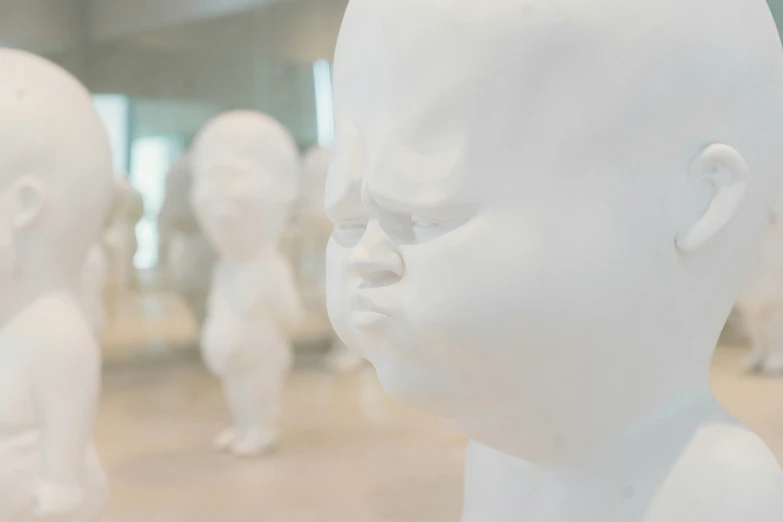 a white mannequin head sitting behind a white sculpture