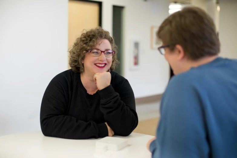 a woman smiling and sitting at a table