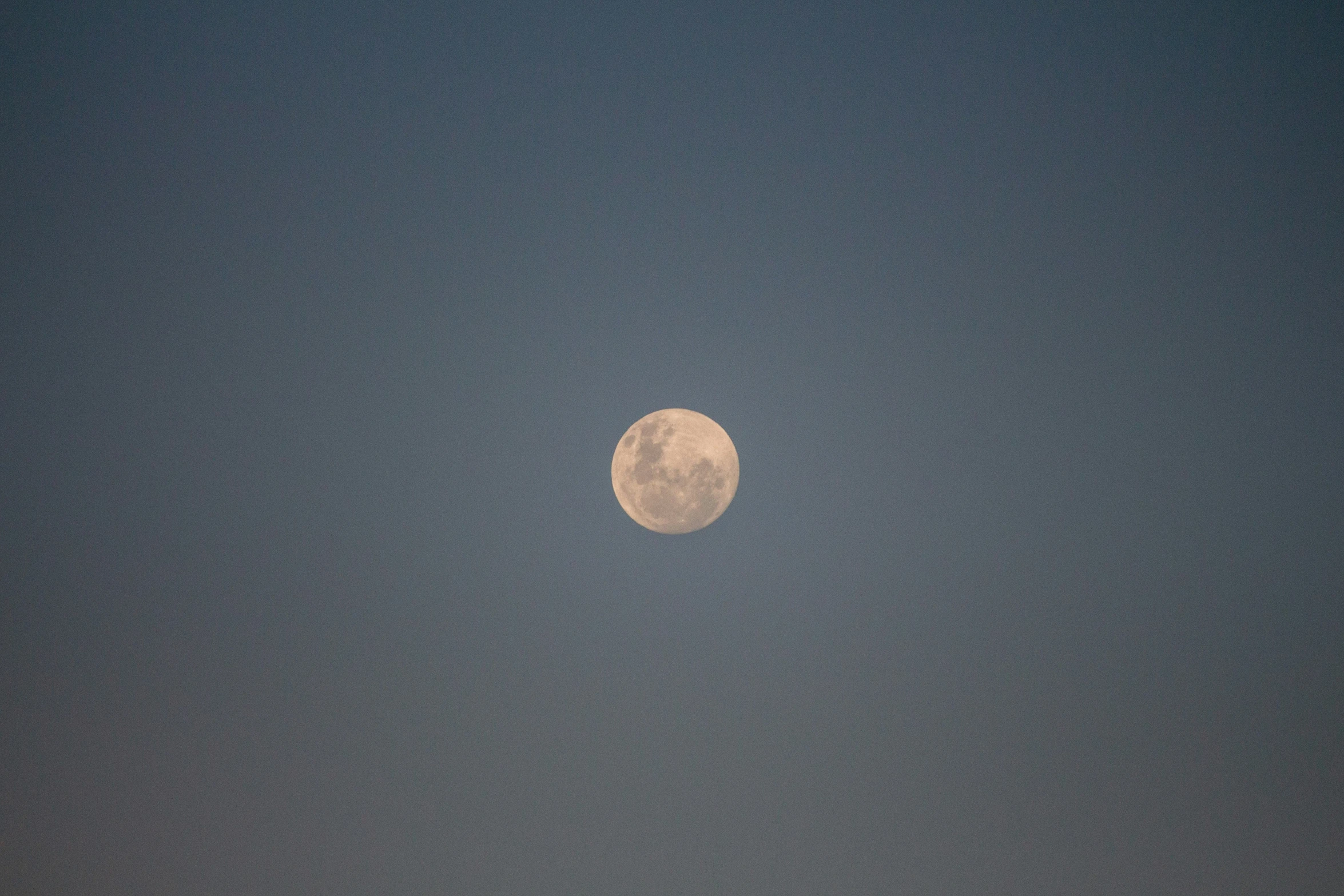 a very large moon is setting in the night sky