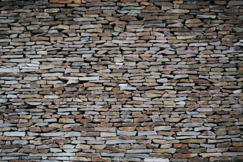 a man walking down the side of a road with a large stone wall