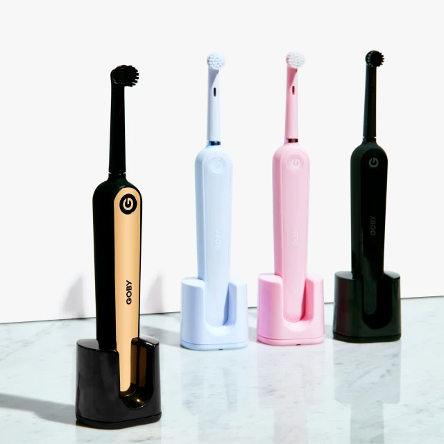 three toothbrushes in different colors, two with white, one pink, two blue