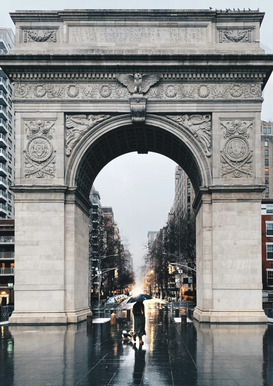 a person walking in the rain through an arch